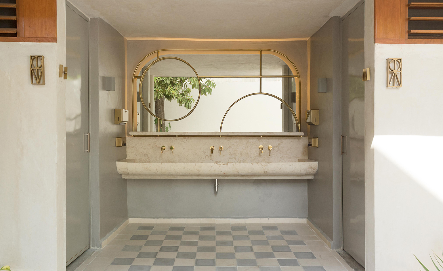 Lagalá bathroom with marble vanity, brass taps and mirror with brass circles and grey and white floor tiles