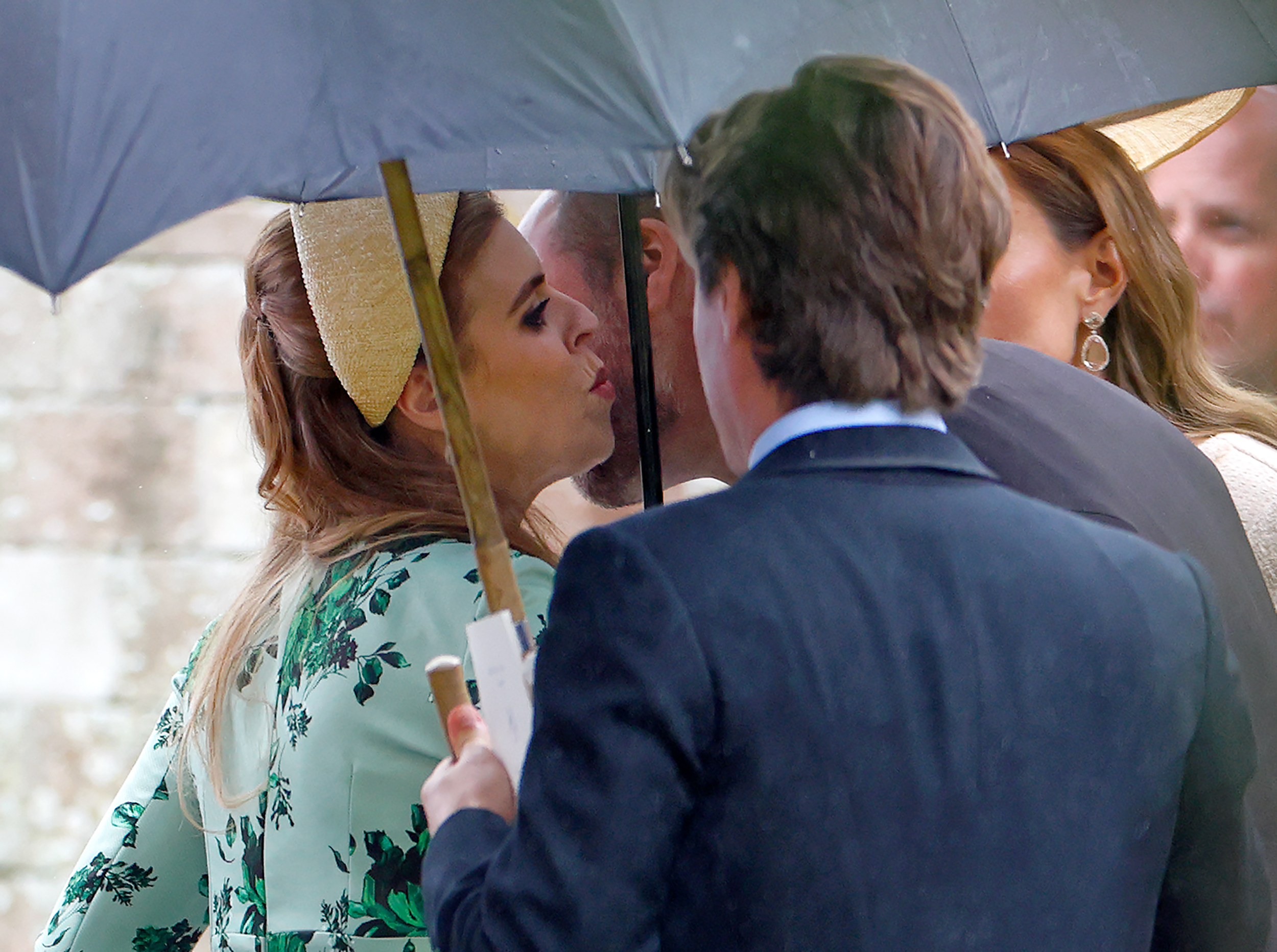 Princess Beatrice kissing Prince William on the cheek under an umbrella