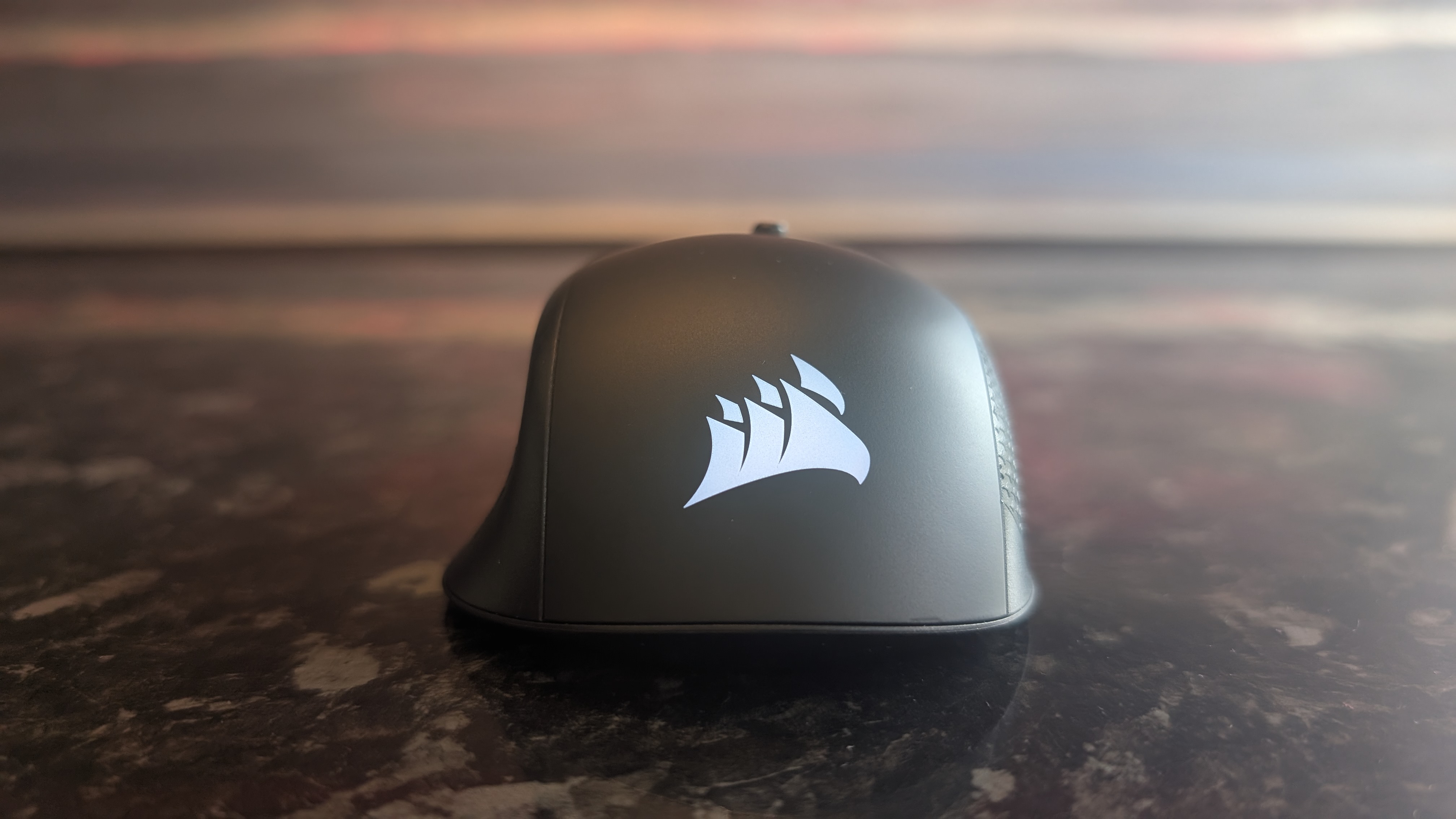 The Corsair Harpoon V2 Wireless gaming mouse pictured on a dark marble worktop.