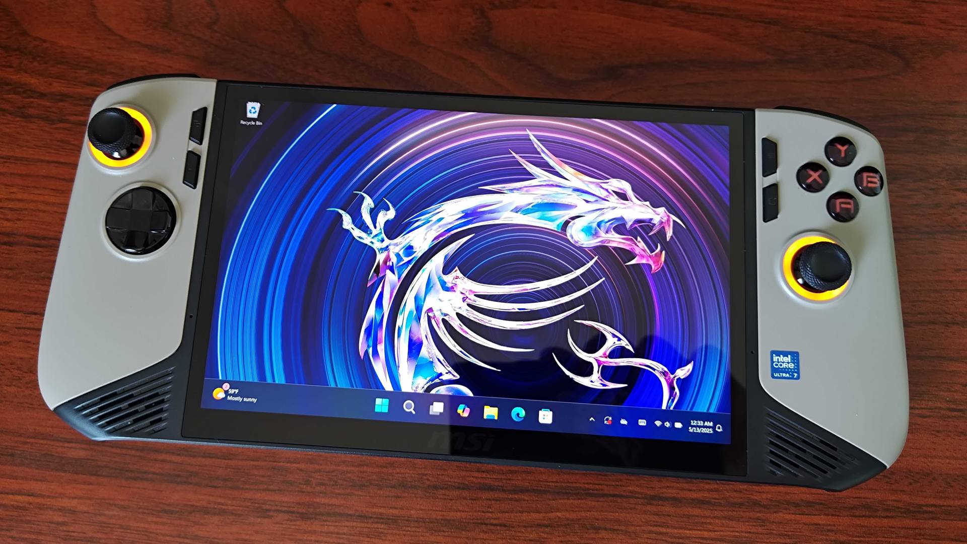 MSI Claw 8 AI+ handheld on woodgrain desk with Windows 11 on screen featuring dragon wallpaper.