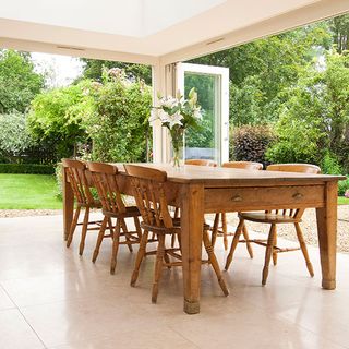 cream limestone tiles with dining table and wooden chairs with flower vase