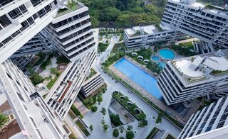 Daytime aerial view of 'The Interlace' urban habitat building roof tops, balconies and pool areas, surrounding landscaping of trees, shrubs and grass verges, roads