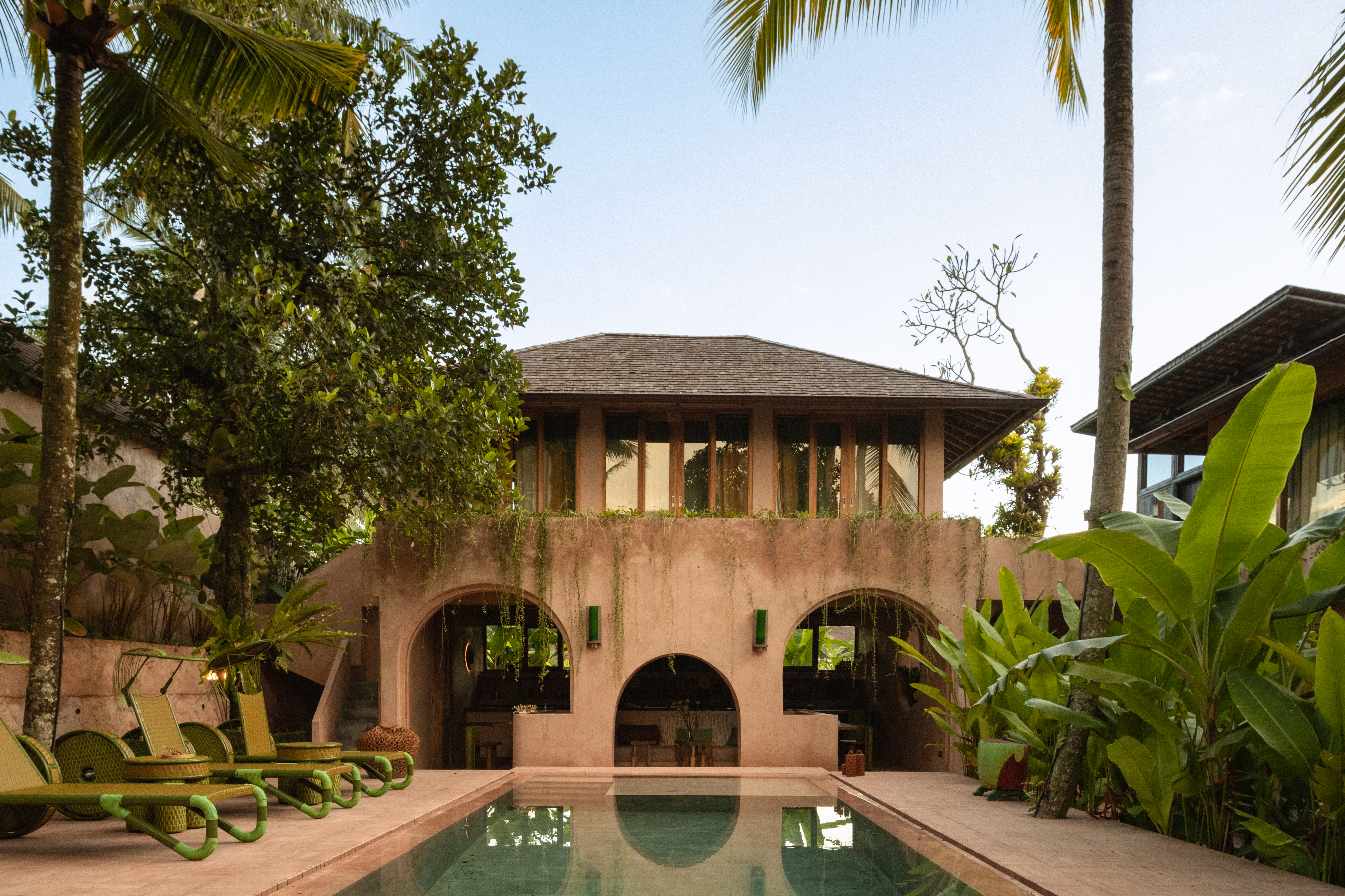 Interiors of a tropical interiors with curved passageways, terracotta walls, colorful curtains, woody furniture, color pops, and nature all around.