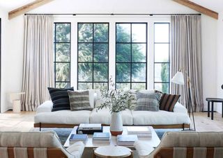 Farmhouse decor ideas, large living room with floor to ceiling windows, white and wood sofa, two gray armchairs, white coffee table, floor lamp