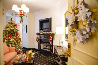 A Christmas tree and garland and fireplace inside the Sleigh Bell Suite at the French Quarter Inn in Charleston, South Carolina