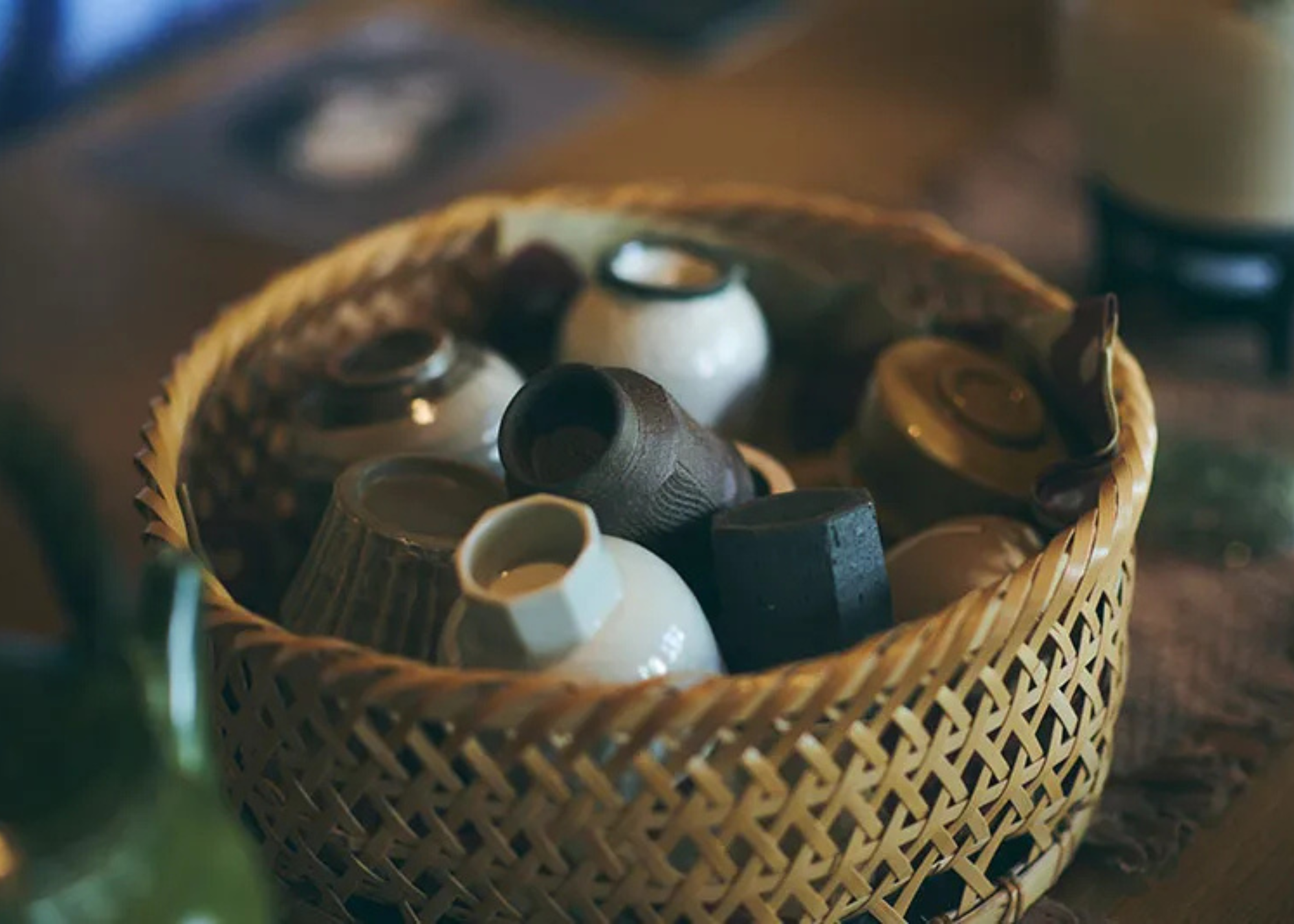 A close-up of a woven bowl full of ceramic cups