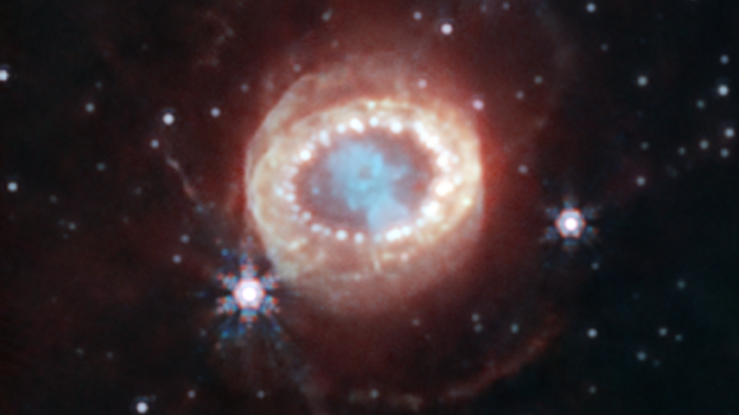 A sort of hazy, blurred ring of light is seen against the backdrop of space. In the center of the ring is a blueish glow.