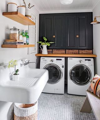 Marble tiled mudroom laundry area with sink, wooden shelving, twin washing machine and baskets