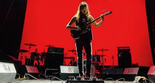Toshi Dorji plays live and is silhouetted against a deep red background.