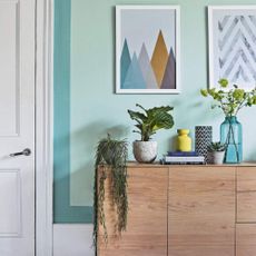 Living room with black painted floor, mint green walls and wooden sideboard