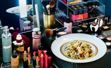 Plate of food on a table with make up products displayed around it