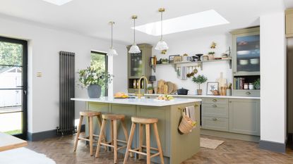 olive green kitchen cabinets with white worktop holding an assortment of items