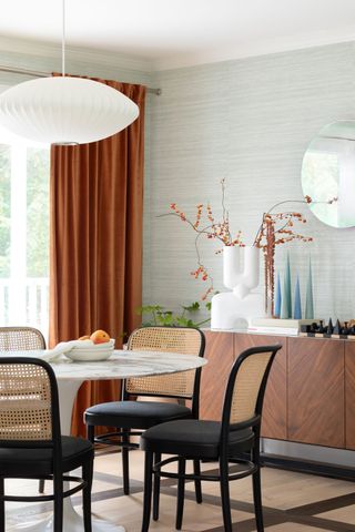 a dining room with black chairs and rust color curtains