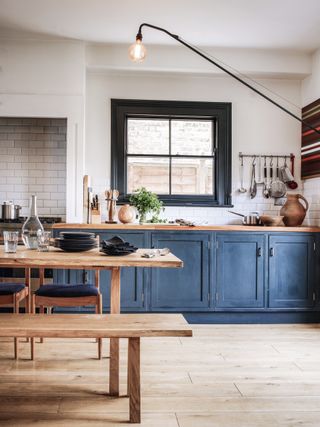 a rustic dark blue kitchen with wooden floors and a wooden table
