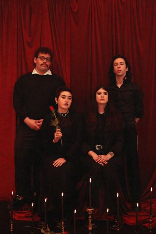 A portrait of Destroy Boys posed in front of a red backdrop