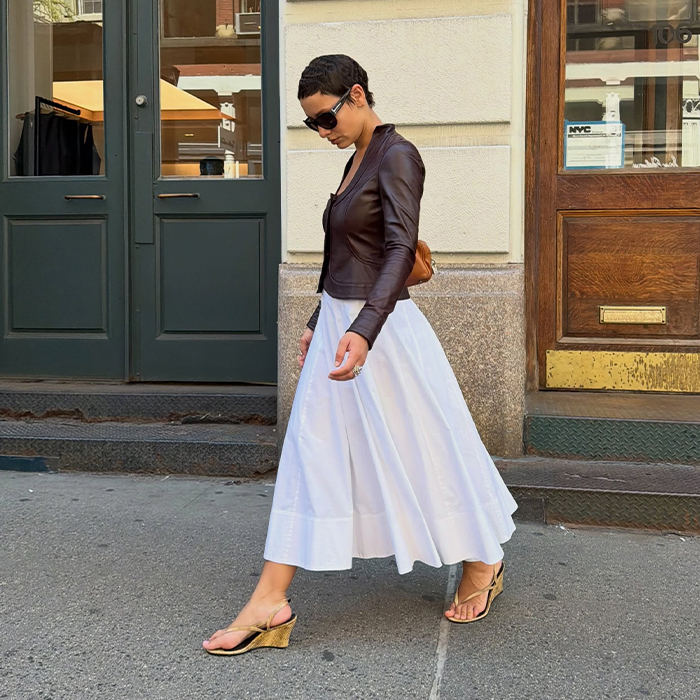 Aisha wears white dress, leather jacket, and wedged heels. 