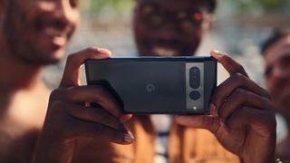 A man holding up the Pixel 7 with the back of the camera in view