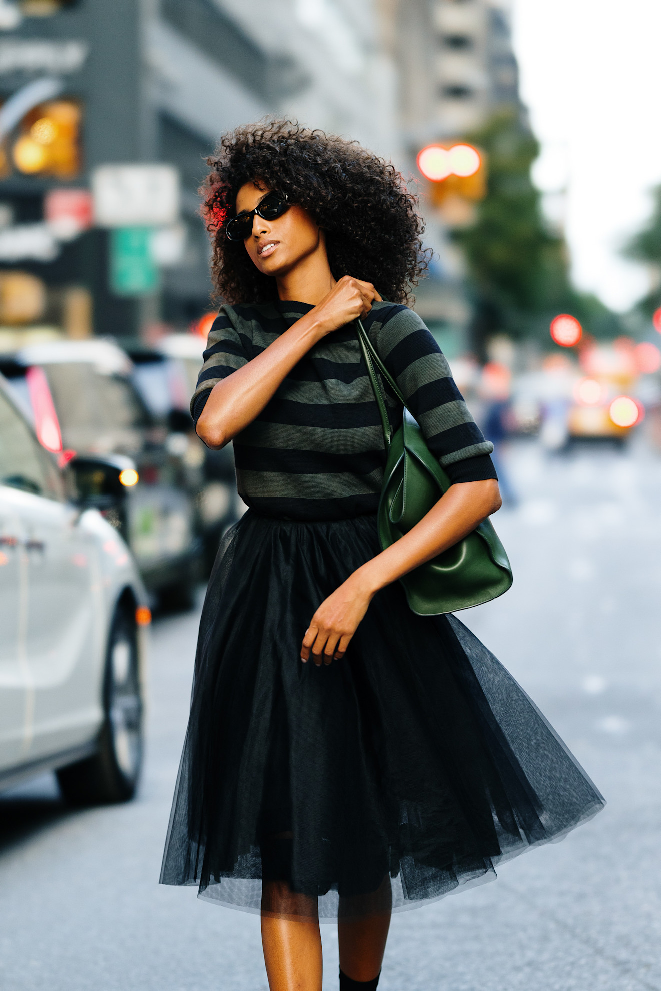a woman with dark curly hair wearing a striped shirt and black tulle skirt during new york fashion week