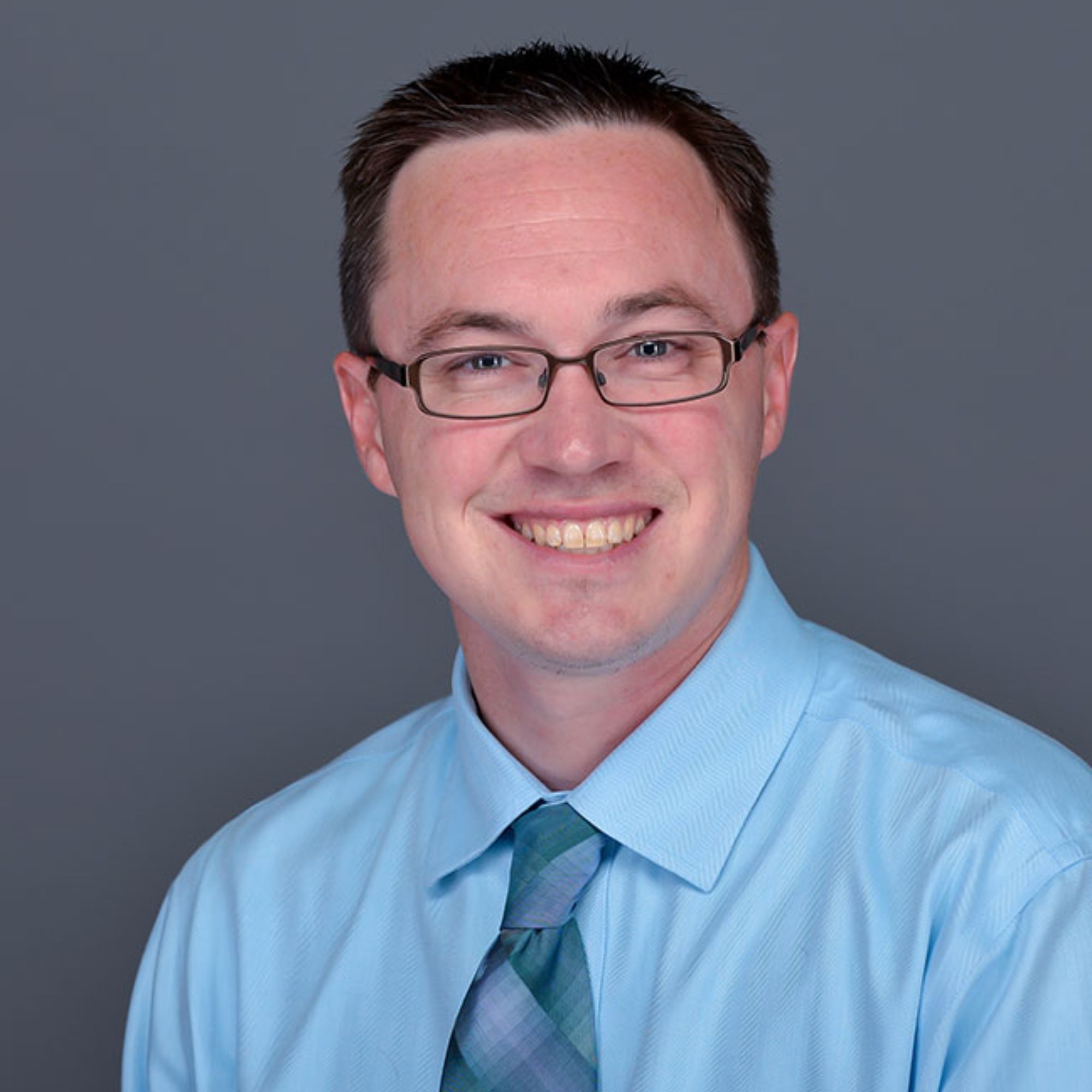 A headshot of Dr. Andrew Gall wearing a blue shirt
