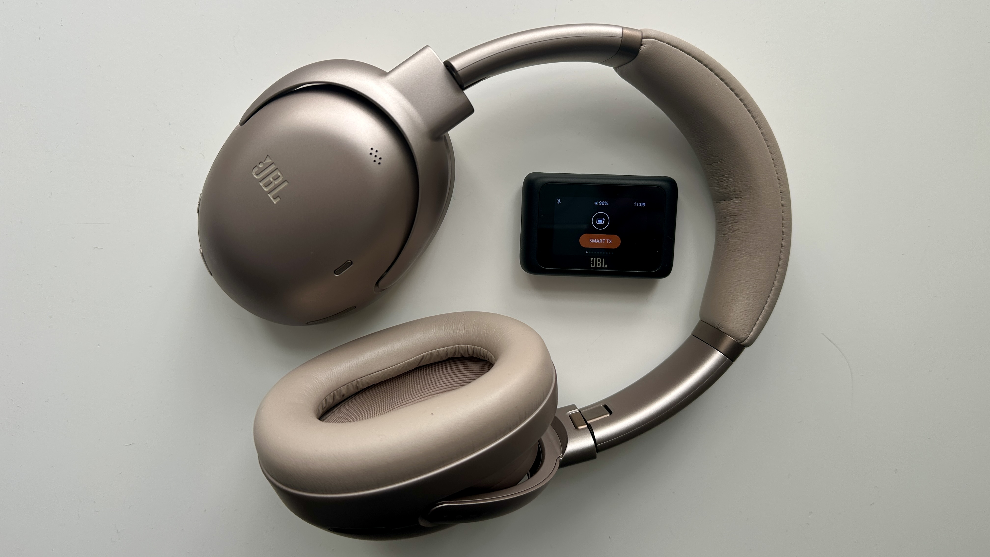 JBL Tour One M3 over-ear noise-cancelling headphones, with the optional Smart Tx transmitter, on a white surface