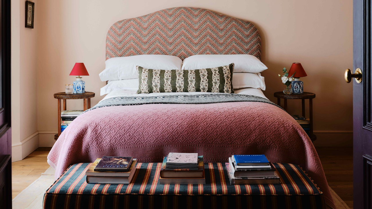Pattern-filled bedroom featuring a striped bench, purple quilt, herringbone headboard, and two-tone bedside lamps