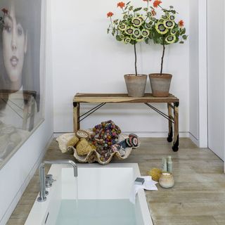 bathroom with wooden side trolley table and bathtub and wooden flooring