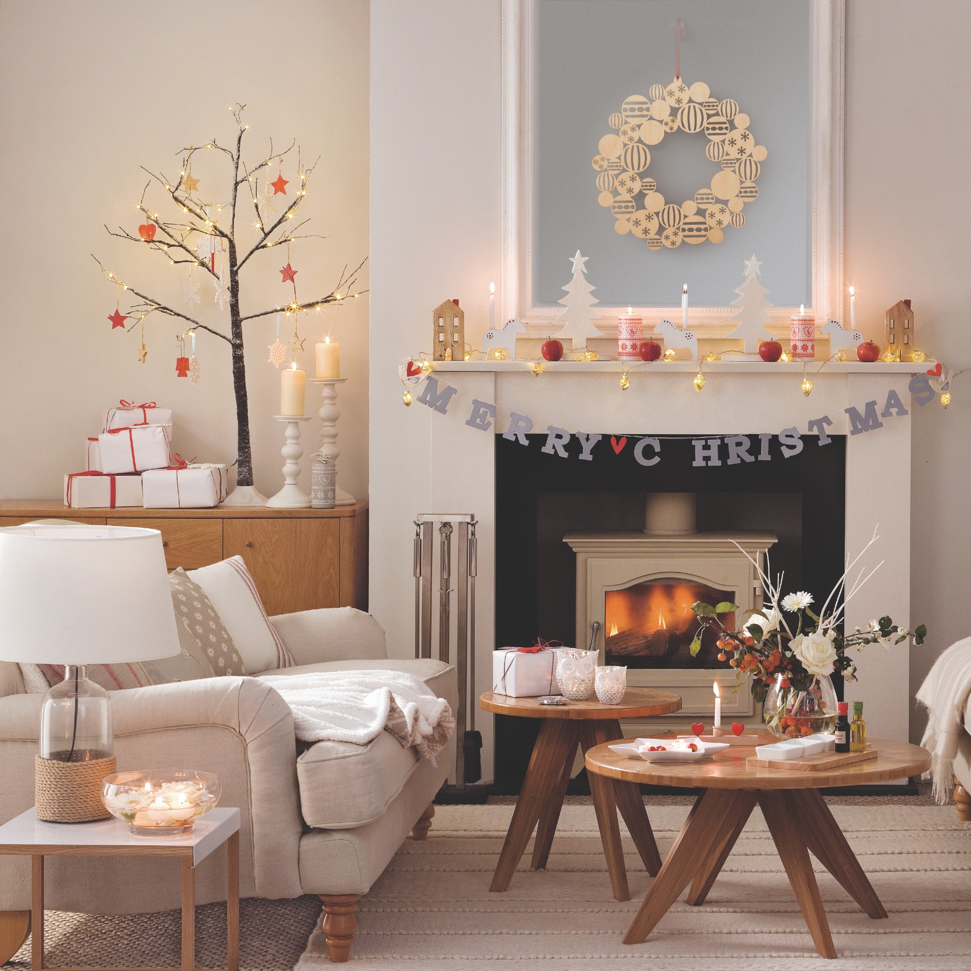 A Scandi-style living room decorated for Christmas with a small twig tree on top of a sideboard
