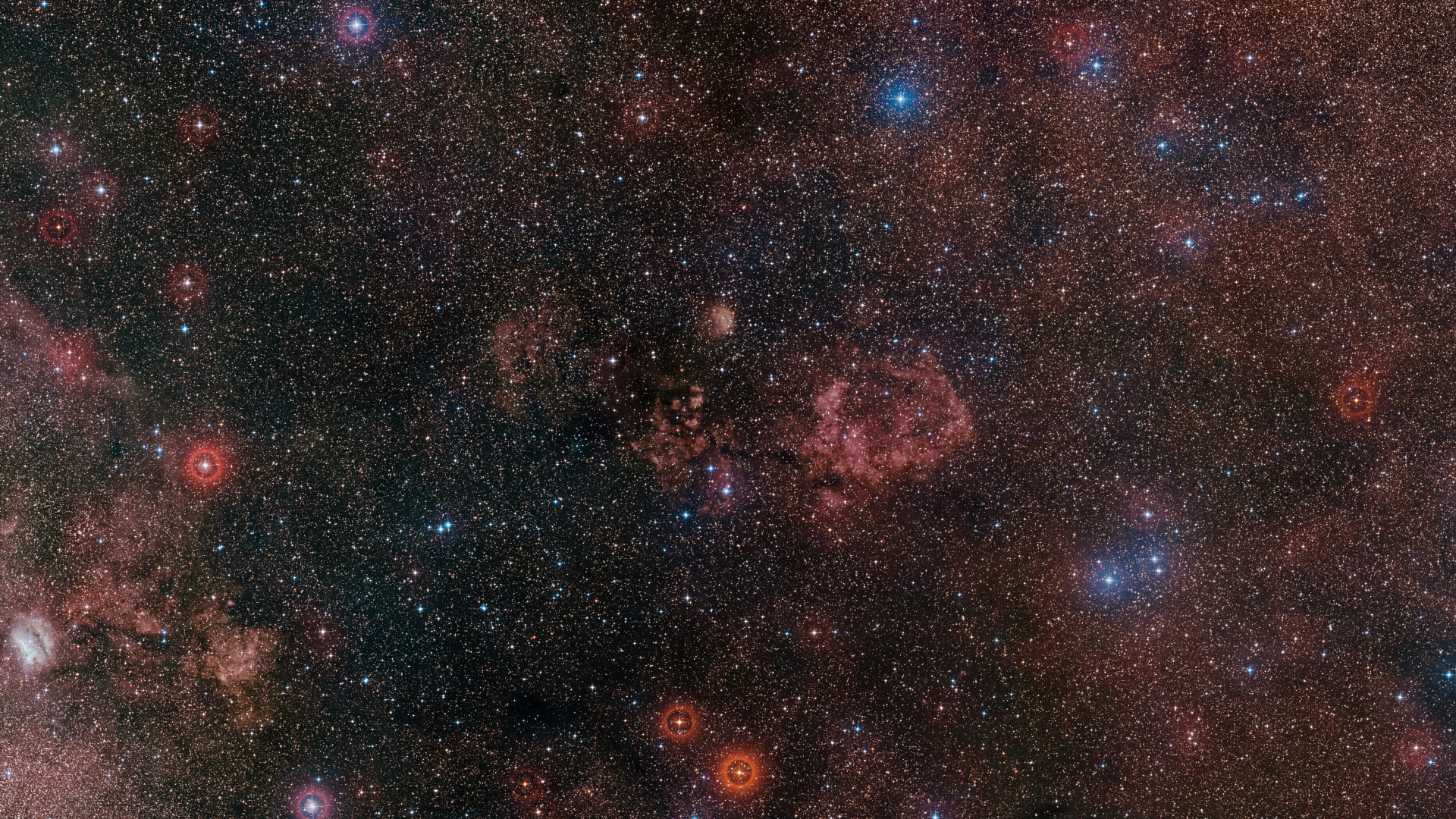 A deep space scene is pictured featuring glowing red nebula clouds that form the outline of a bat's body and wings, threaded with dark filaments of interstellar gas against a teeming starfield.