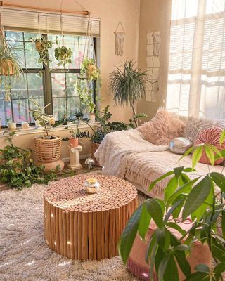 Modern boho living room with textures throws, wooden round coffee table and large collection of houseplants