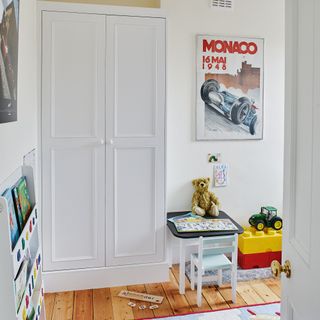 kids room with white walls timber flooring toys and original Victorian built in cupboard