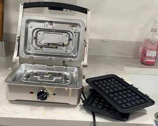 A Cuisinart waffle and pancake maker with plates removed on marble countertop