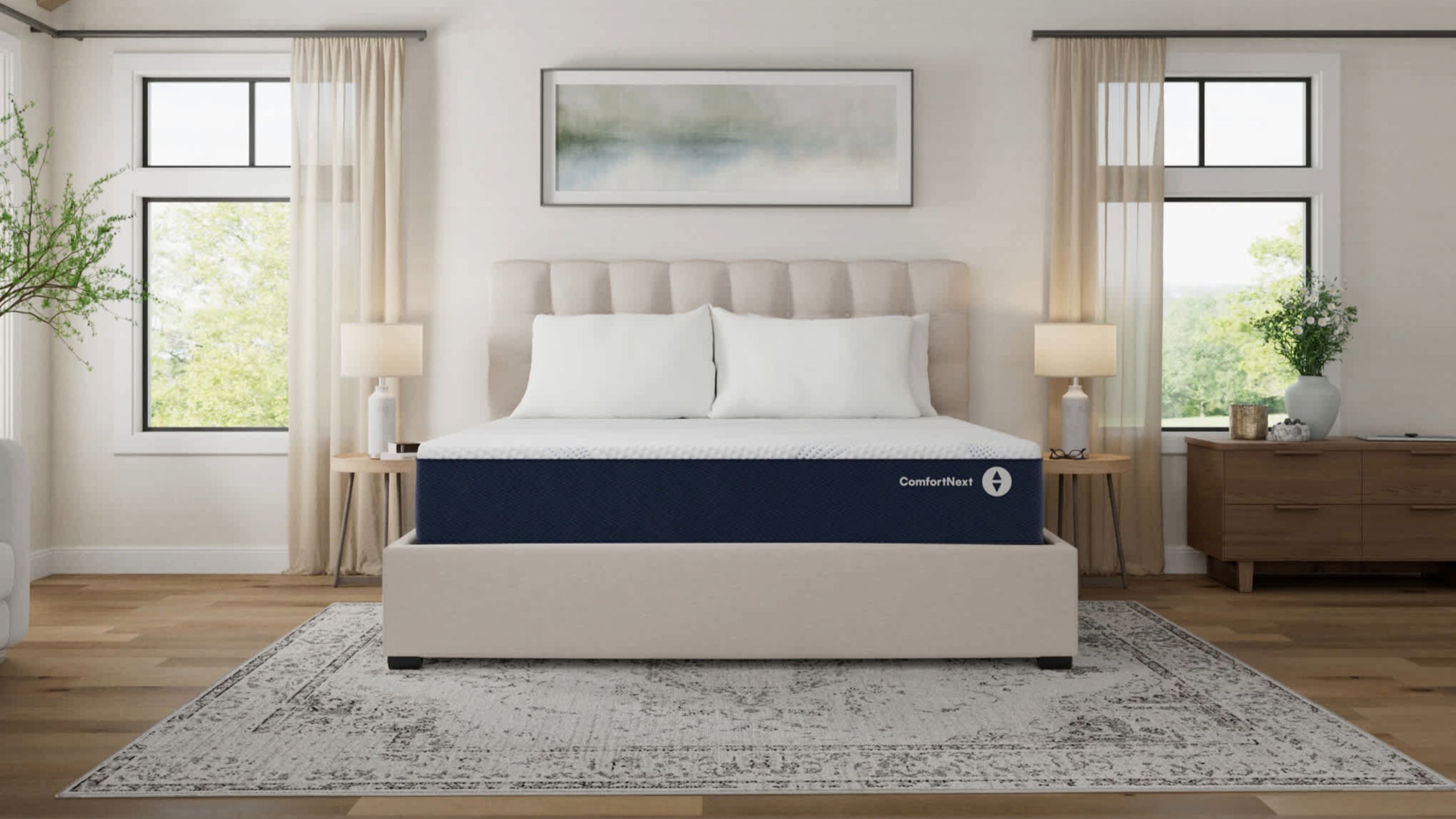 Sleep Number Comfort Next mattress on a white fluted bed frame with large windows either side in a white bedroom with light wood flooring and a patterned rug.