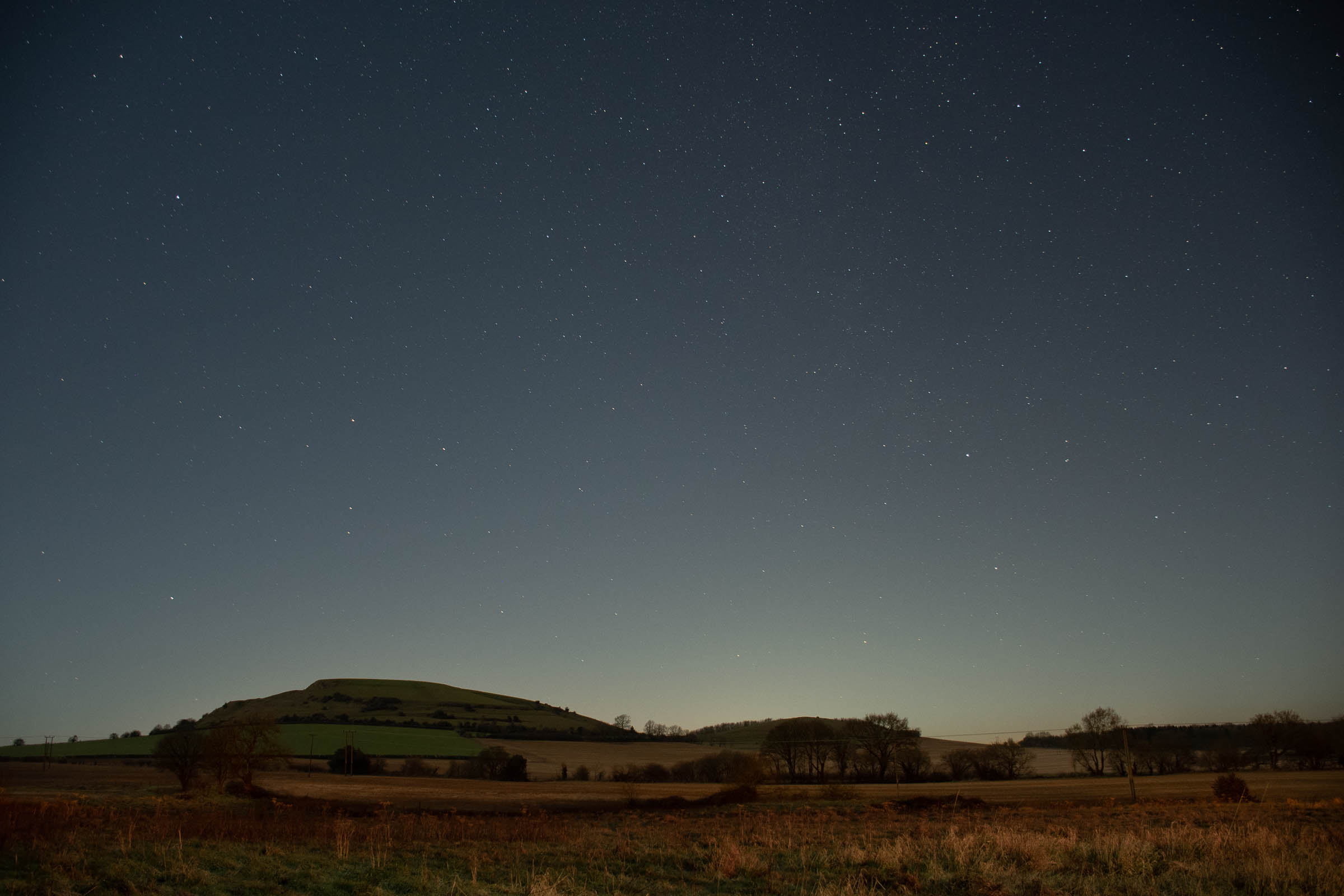 Astrophotography taken with the Nikon D7500 showing a hill underneath the night sky
