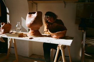 Kana's London studio, featuring wide argilla sculptures on her worktable.