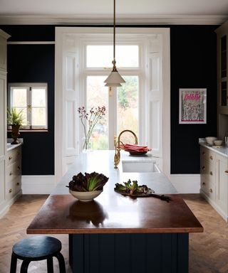 can you fit an island in a galley kitchen, copper and white countertop, herringbone floor, basin in island, black walls, stone cabinetry
