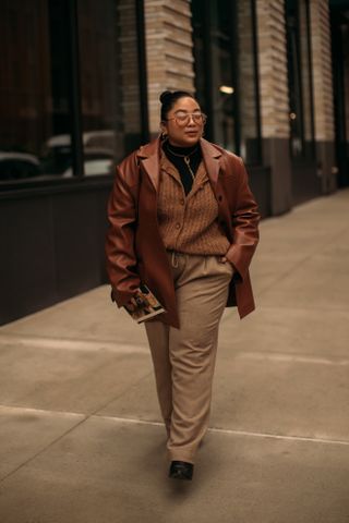 woman wearing leather jacket, cardigan, and trousers