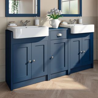 Run of built-in blue bathroom cupboards with twin basins