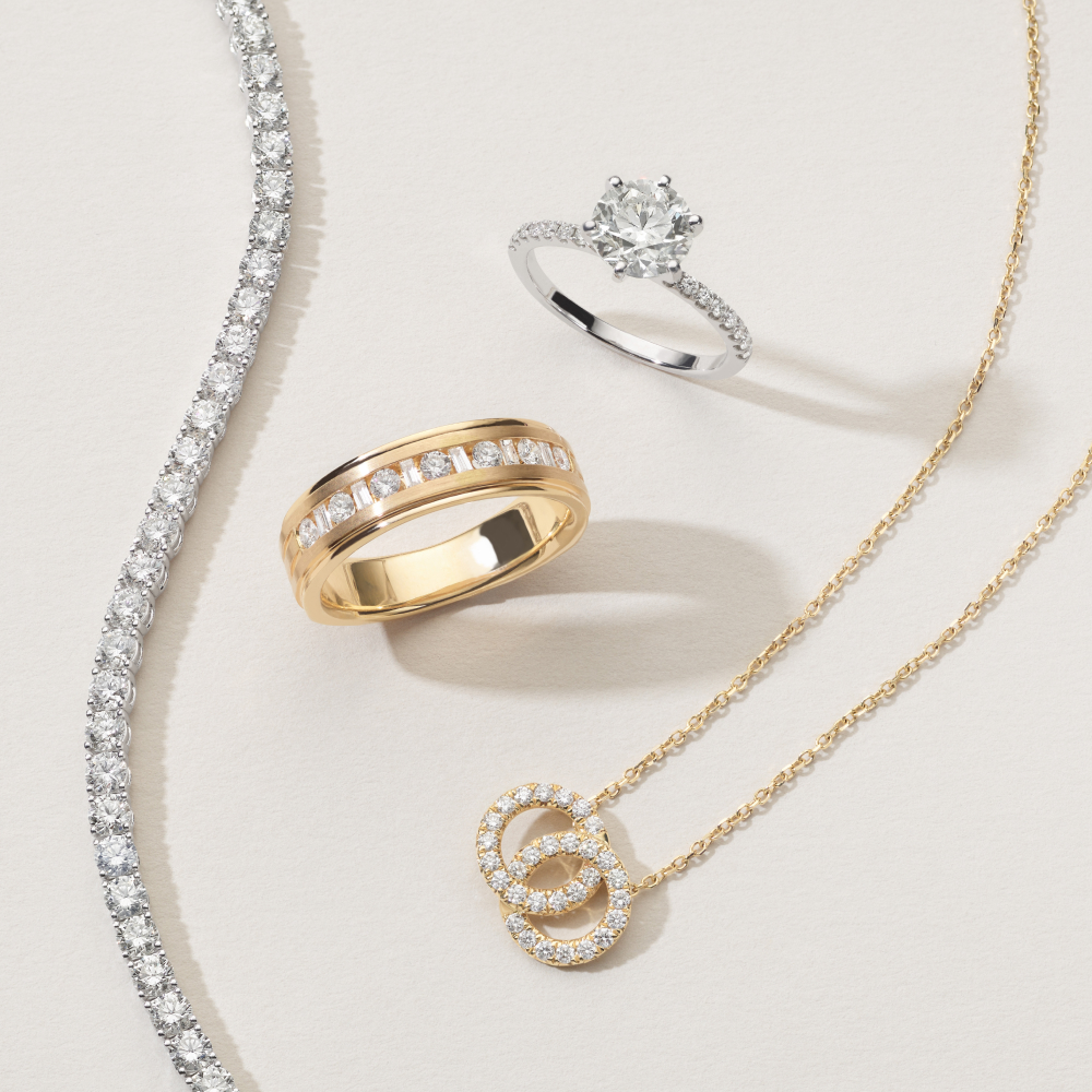 A silver diamond ring, along with a thick, gold wedding band, a gold necklace, and a silver diamond necklace from Shane Co.