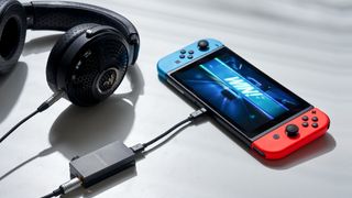 Astell & Kern HB1 attached to a set of headphones and a Nintendo switch, on a white table