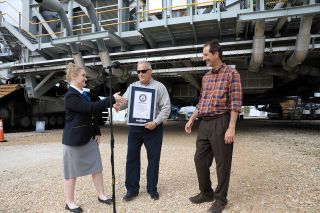 Guinness World Records adjudicator Hannah Ortman reaches out to shake hands with Brett Raulerson, Jacobs TOSC Crawlers, Transporters and Structures group manager, left, and John Giles, NASA's Crawler Element Operations manager, at a ceremony at Kennedy Space Center on March 29, 2023.
