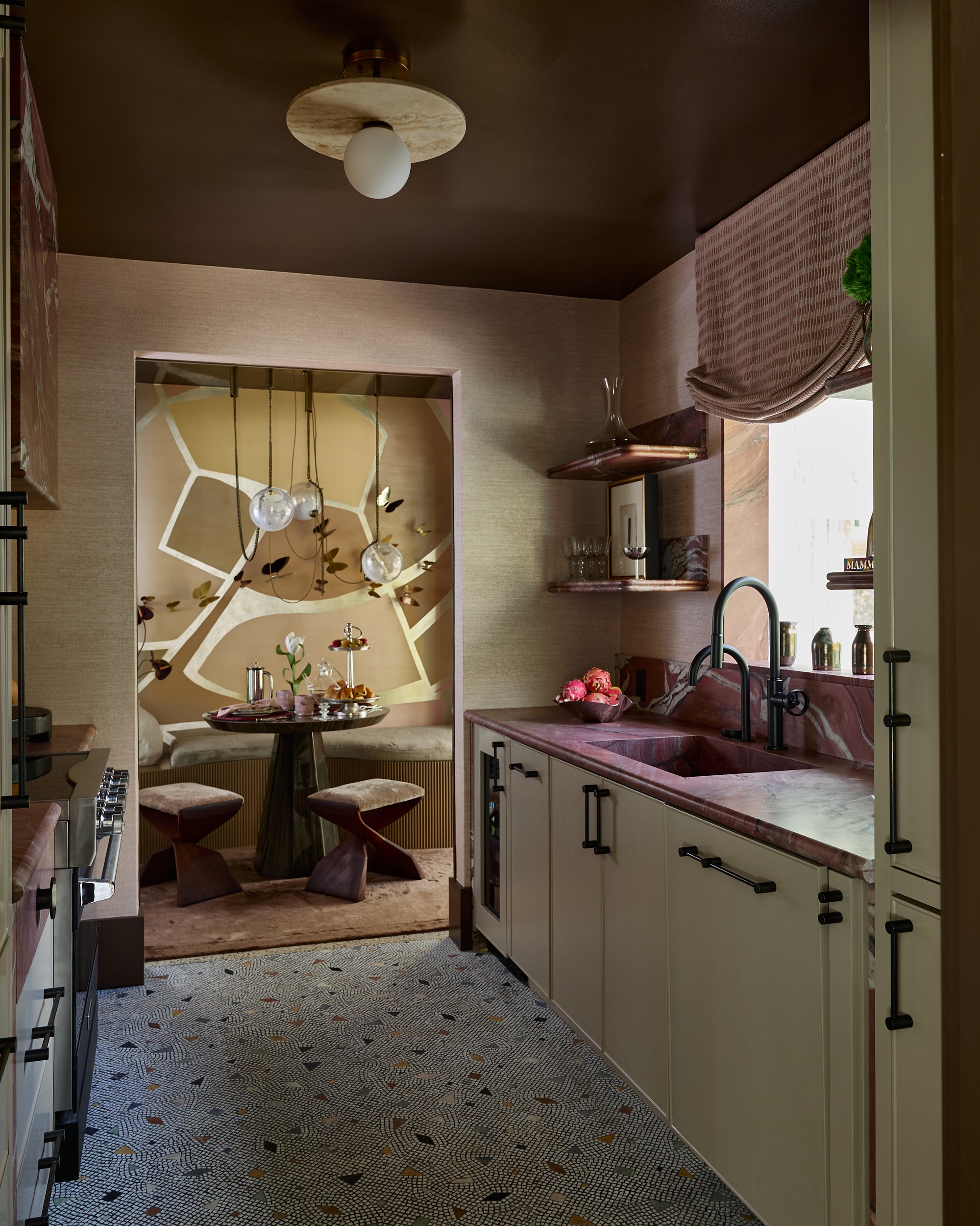 a small kitchen with red countertops and a mosaic floor