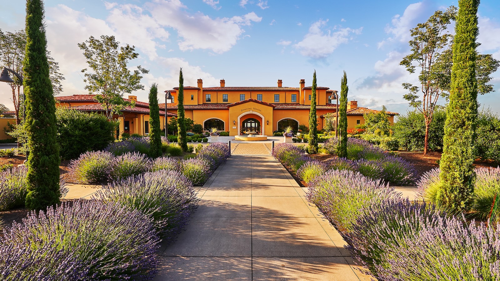 The exterior of the Domaine Serene winery and hospitality building with a walkway and gardens in the foreground.