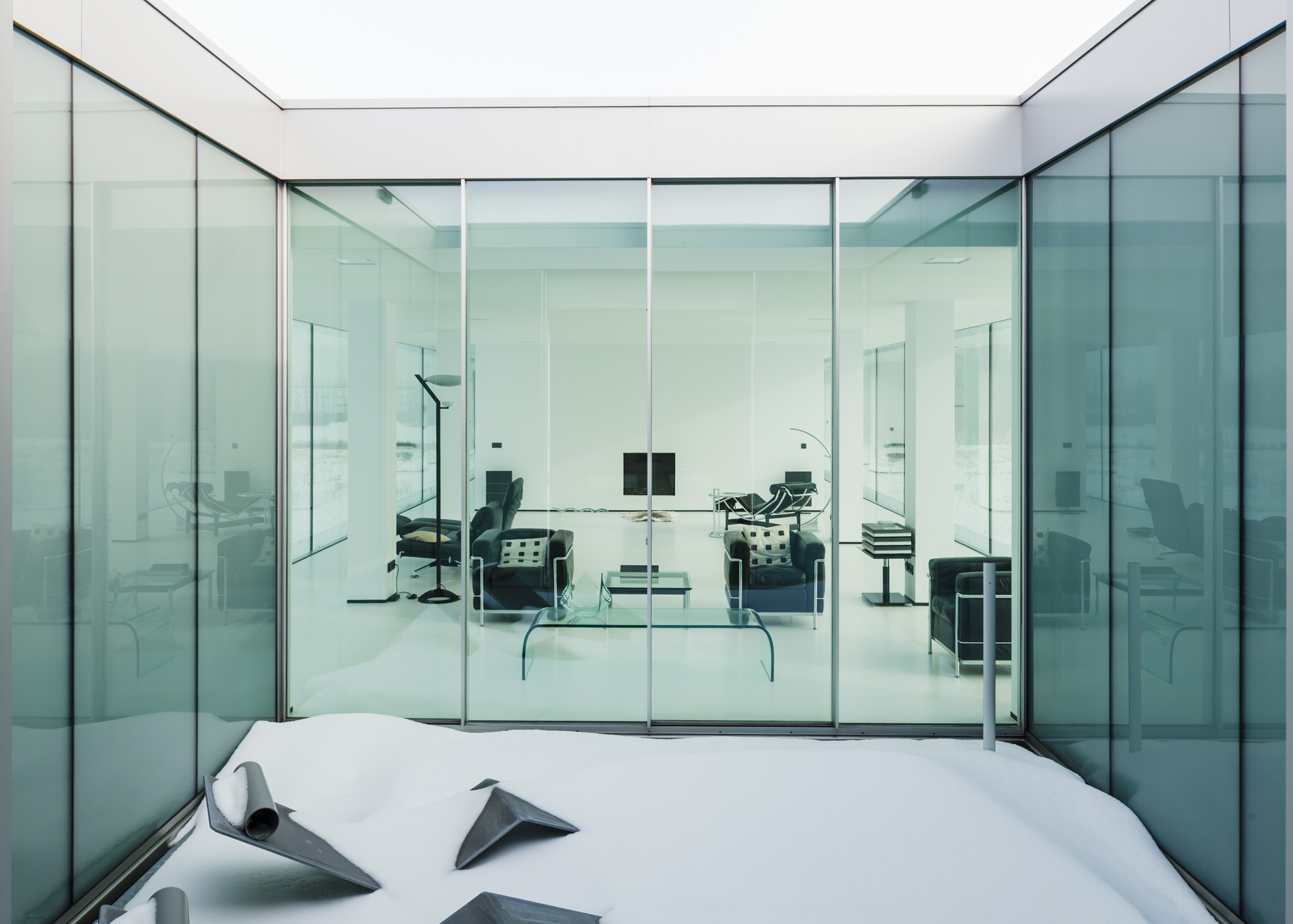 The view of the living room from the snowy patio, seen through floor-to-ceiling glass.