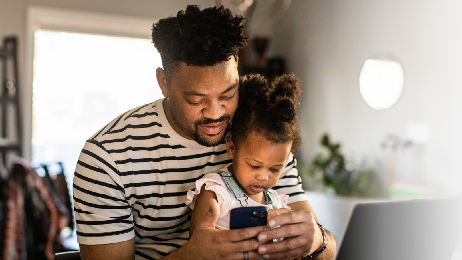 A father and daughter looking at their respective smartphones.