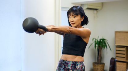A woman performing a kettlebell swing at home 