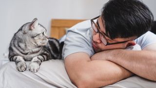 Man and cat lying on bed