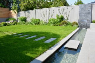 lawn lined with water feature in garden by Tom Howard