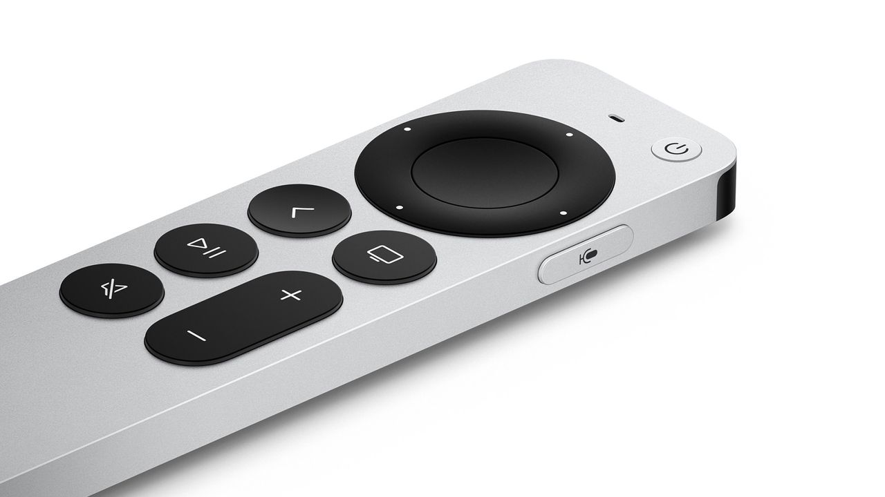A close-up of the silver remote for an Apple TV 4K streamer, It has black buttons and is sitting on a white surface.