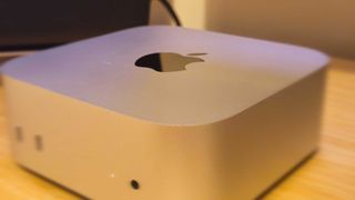 A silver Apple Mac mini (M4) on a wooden desk