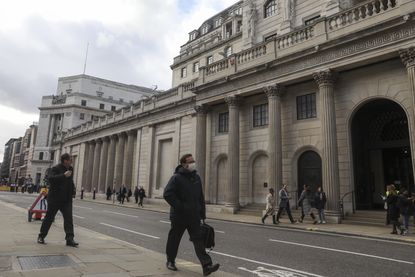 A pedestrian wearing a protective face mask walks past the the Bank of England in the City of London